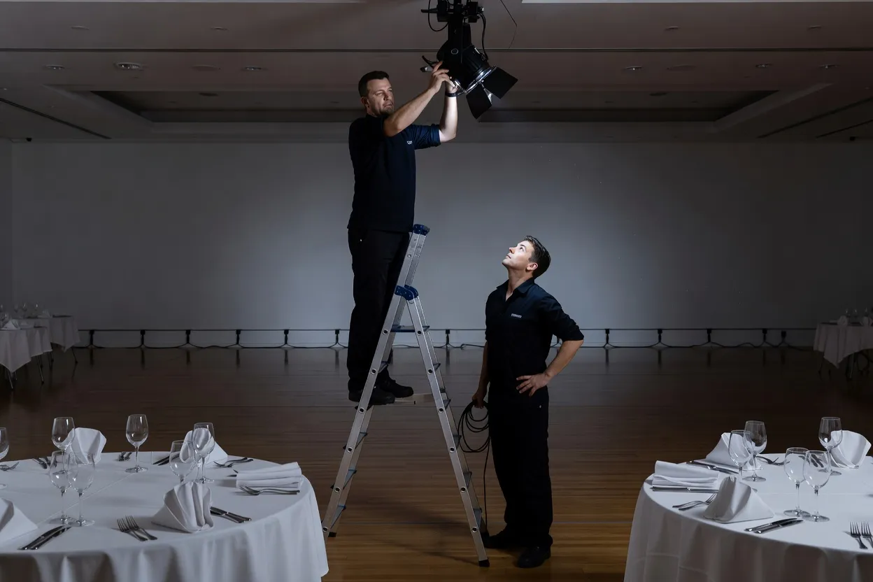 Régisseur lumière réglant les projecteurs d'une salle de mariage avant l'arrivée des invités